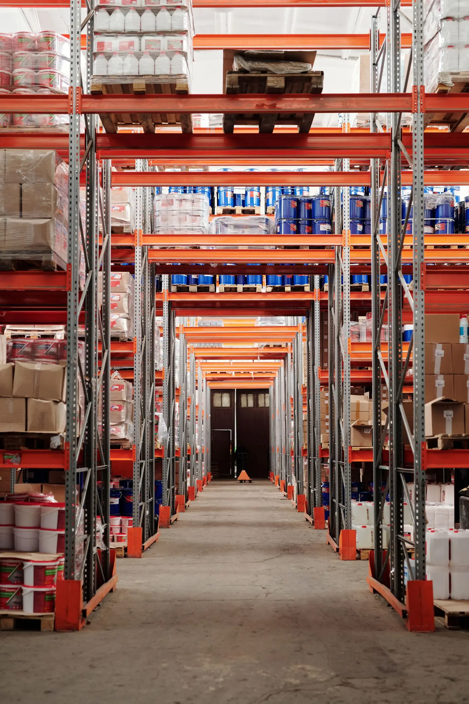 Allée d’entrepôt avec des rayonnages orange chargés de marchandises palettisées